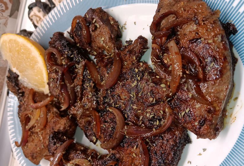 sikoti tigani me kremmidia Ζουμερό συκώτι στο τηγάνι με καραμελωμένα κρεμμύδια, σε πιάτο σερβιρίσματος.