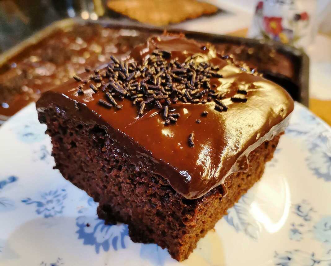 Κοντινή λήψη σε κομμάτι σοκολατόπιτας με πλούσιο γλάσο και ξύσμα πορτοκαλιού