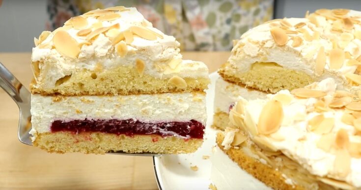 Κομμάτι από Τούρτα Παραδεισένια, που αναδεικνύει τις διαφορετικές στρώσεις: αφράτο κέικ, τραγανή μαρέγκα, κόκκινη γέμιση φράουλας και λευκή κρέμα τυριού