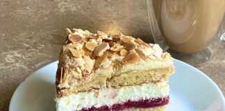 Κομμάτι από Τούρτα Παραδεισένια, που αναδεικνύει τις διαφορετικές στρώσεις: αφράτο κέικ, τραγανή μαρέγκα, κόκκινη γέμιση φράουλας και λευκή κρέμα τυριού