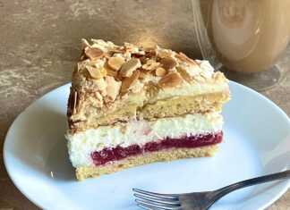 Κομμάτι από Τούρτα Παραδεισένια, που αναδεικνύει τις διαφορετικές στρώσεις: αφράτο κέικ, τραγανή μαρέγκα, κόκκινη γέμιση φράουλας και λευκή κρέμα τυριού