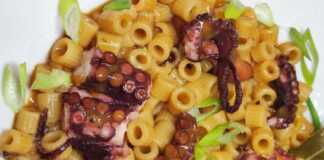 Ολοκληρωμένο Χταπόδι με Μακαρονάκι Κοφτό σε πιάτο, με πλούσια κόκκινη σάλτσα και ψιλοκομμένο μαϊντανό.