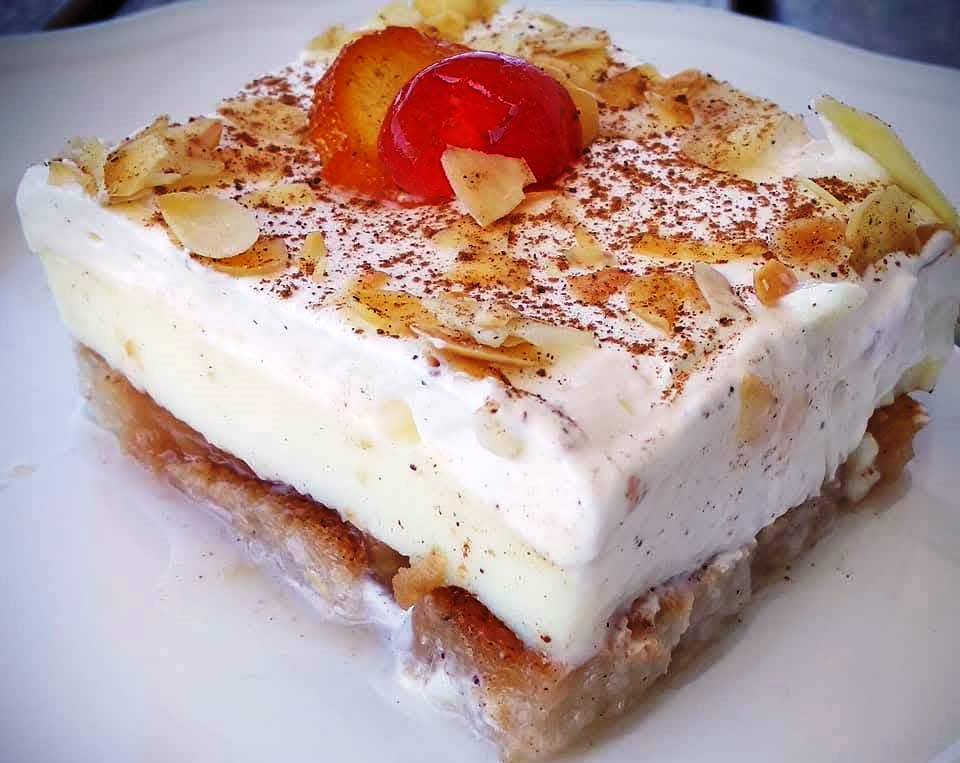 zakinthini frigania0 Κομμάτι από εκμέκ φρυγανιά, με ορατά τα στρώματα και τη γαρνιτούρα αμυγδάλου και γλυκού του κουταλιού.