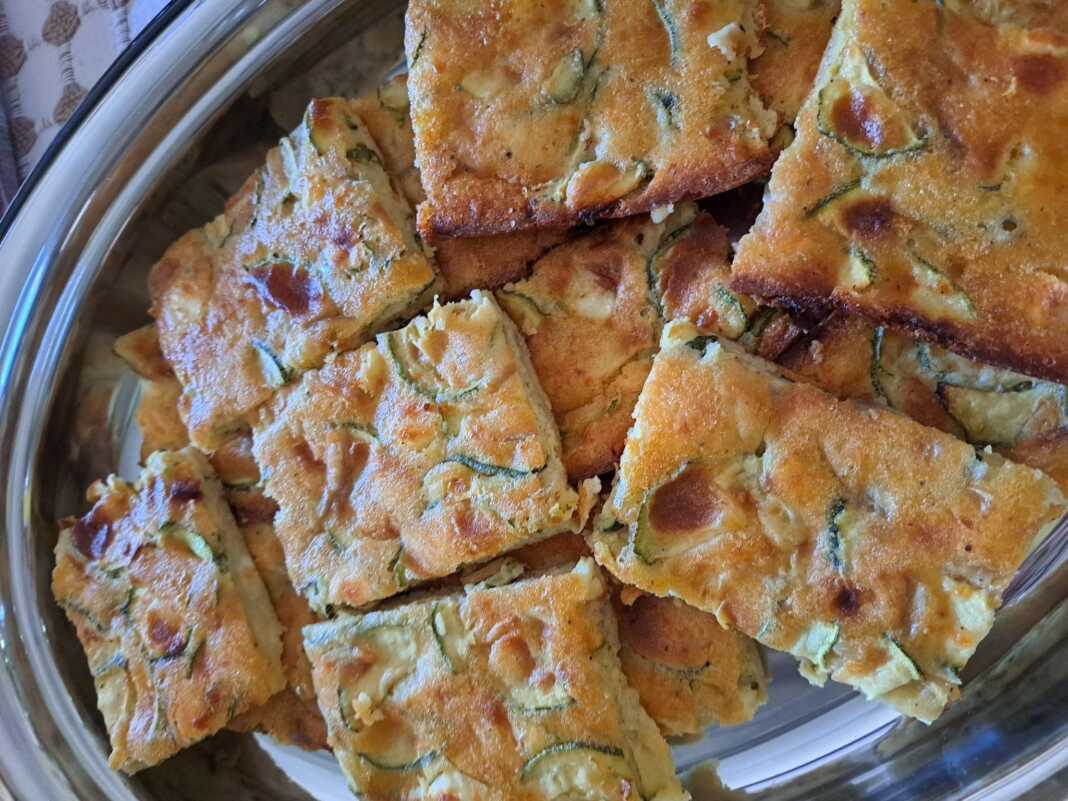 Κομμένο κομμάτι από την κολοκυθόπιτα που αναδεικνύει τα κολοκυθάκια και τη φέτα μέσα στη ζύμη.