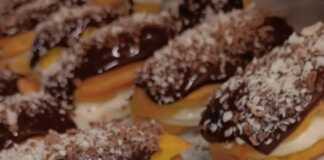 Ένα ταψί με γεμισμένα εκλεράκια, καλυμμένα με σοκολάτα και διακοσμημένα με κουβερτούρα