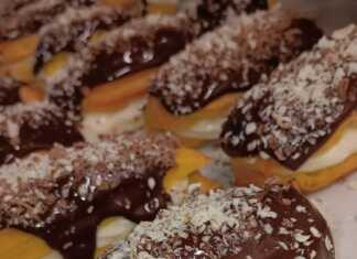 Ένα ταψί με γεμισμένα εκλεράκια, καλυμμένα με σοκολάτα και διακοσμημένα με κουβερτούρα