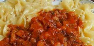 Ζυμαρικά φαρφάλες με πλούσια σάλτσα μελιτζάνας, γαρνιρισμένα με φρέσκο βασιλικό, σε πιάτο.