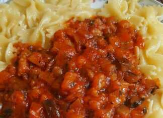 Ζυμαρικά φαρφάλες με πλούσια σάλτσα μελιτζάνας, γαρνιρισμένα με φρέσκο βασιλικό, σε πιάτο.