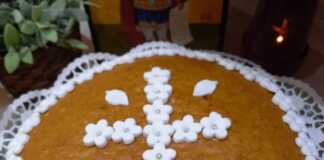 Μια ολόκληρη Φανουρόπιτα σε πιατέλα, πασπαλισμένη με ζάχαρη άχνη και στολισμένη με λευκά λουλουδάκια