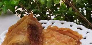 2 κομματια από γλυκιά κολοκυθόπιτα, με τα καρύδια και τις σταφίδες να ξεχωρίζουν μέσα στη γέμιση."