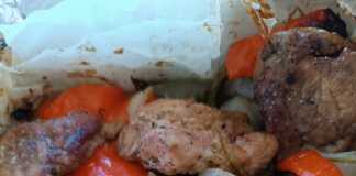 Ένα πιάτο με Χοιρινό με πιπεριές στην λαδόκολλα, με το ζουμερό κρέας και τα λαχανικά σε πρώτο πλάνο