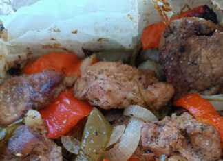 Ένα πιάτο με Χοιρινό με πιπεριές στην λαδόκολλα, με το ζουμερό κρέας και τα λαχανικά σε πρώτο πλάνο