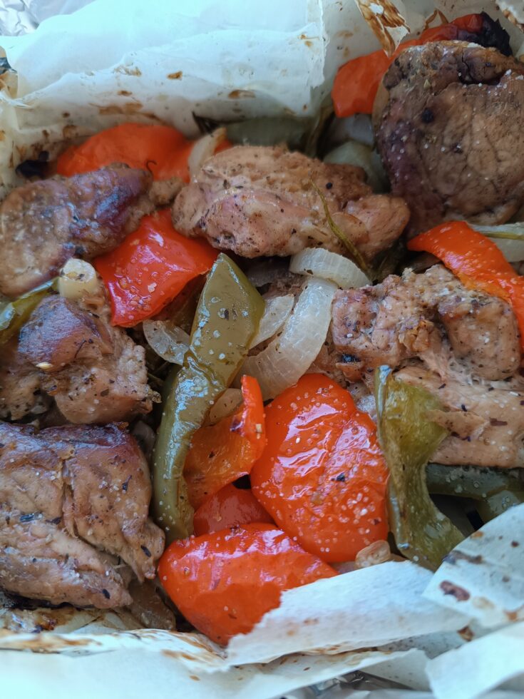 Ένα πιάτο με Χοιρινό με πιπεριές στην λαδόκολλα, με το ζουμερό κρέας και τα λαχανικά σε πρώτο πλάνο