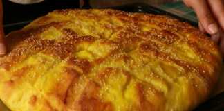 Ένα ολόκληρο αφράτο ψωμί από καλαμπόκι σε ξύλινο πάγκο, με χρυσαφένια κρούστα