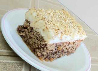 Μια κομμένη φέτα από καρυδόπιτα με κρέμα, που φαίνονται οι στρώσεις του γλυκού και η κρέμα