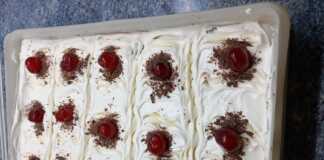 Κοντινό πλάνο σε μια φέτα καρυδόπιτα, που φαίνονται οι τρεις στρώσεις: η καρυδόπιτα, η κρέμα πατισερί και η σαντιγί