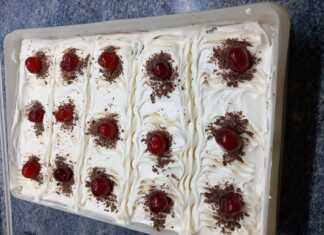 Κοντινό πλάνο σε μια φέτα καρυδόπιτα, που φαίνονται οι τρεις στρώσεις: η καρυδόπιτα, η κρέμα πατισερί και η σαντιγί