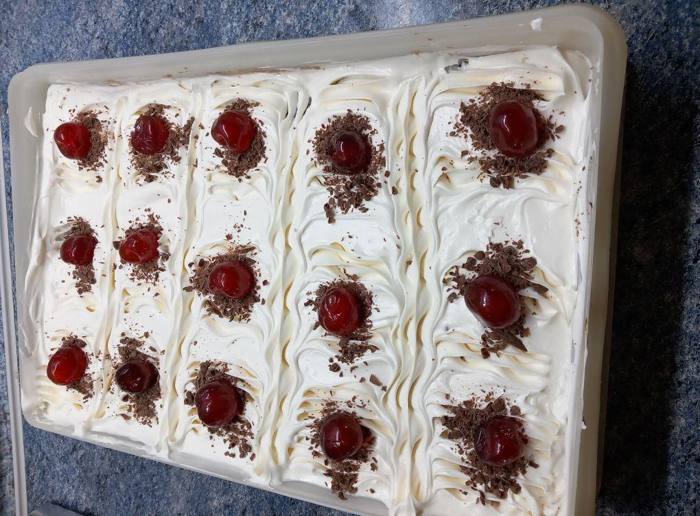 karidopita santigi Κοντινό πλάνο σε μια φέτα καρυδόπιτα, που φαίνονται οι τρεις στρώσεις: η καρυδόπιτα, η κρέμα πατισερί και η σαντιγί