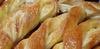 Ένα πιάτο γεμάτο με αφράτα Κουλουράκια πατισερί, πασπαλισμένα με ζάχαρη και μέλι.