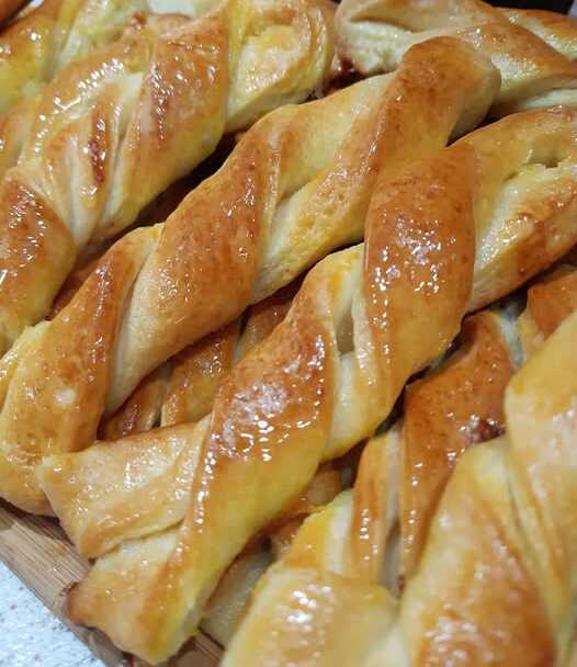 koulourakia patiseri Ένα πιάτο γεμάτο με αφράτα Κουλουράκια πατισερί, πασπαλισμένα με ζάχαρη και μέλι.