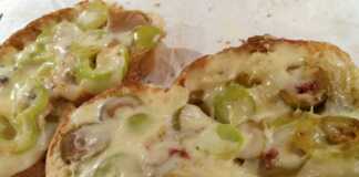 Ένα πιάτο με σκορδόψωμα στην τοστιέρα, με λιωμένο τυρί και τα υλικά από πάνω, φτιαγμένο από μπαγιάτικο ψωμί