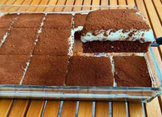 Ένα ολόκληρο σοκολατένιο κέικ με κρέμα και καφέ, πασπαλισμένο με κακάο, σε πιατέλα, έτοιμο για σερβίρισμα