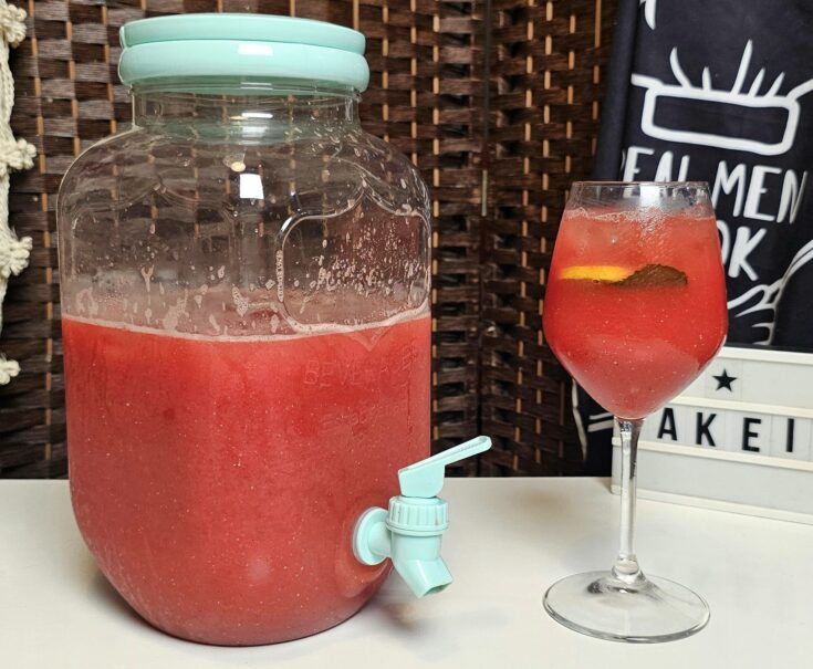 Δροσιστική σπιτική καρπουζάδα σε γυάλινη κανάτα, με φέτες καρπουζιού, παγάκια και φύλλα δυόσμου.