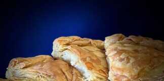 Μια στρογγυλή Τυρόπιτα με φυλλωτή, χρυσαφένια και τραγανή, έτοιμη να κοπε