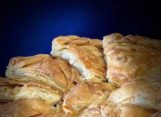 Μια στρογγυλή Τυρόπιτα με φυλλωτή, χρυσαφένια και τραγανή, έτοιμη να κοπε