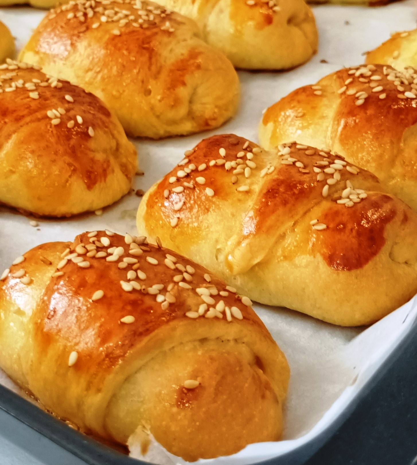 Ένα ταψί γεμάτο με αφράτα τυροπιτάκια, φρεσκοψημένα με χρυσαφένιο χρώμα.