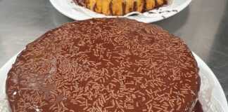 Μια ολόκληρη Τούρτα Κωκ, καλυμμένη με γυαλιστερό γλάσο σοκολάτας, σε λευκή πιατέλα