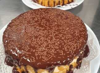 Μια ολόκληρη Τούρτα Κωκ, καλυμμένη με γυαλιστερό γλάσο σοκολάτας, σε λευκή πιατέλα