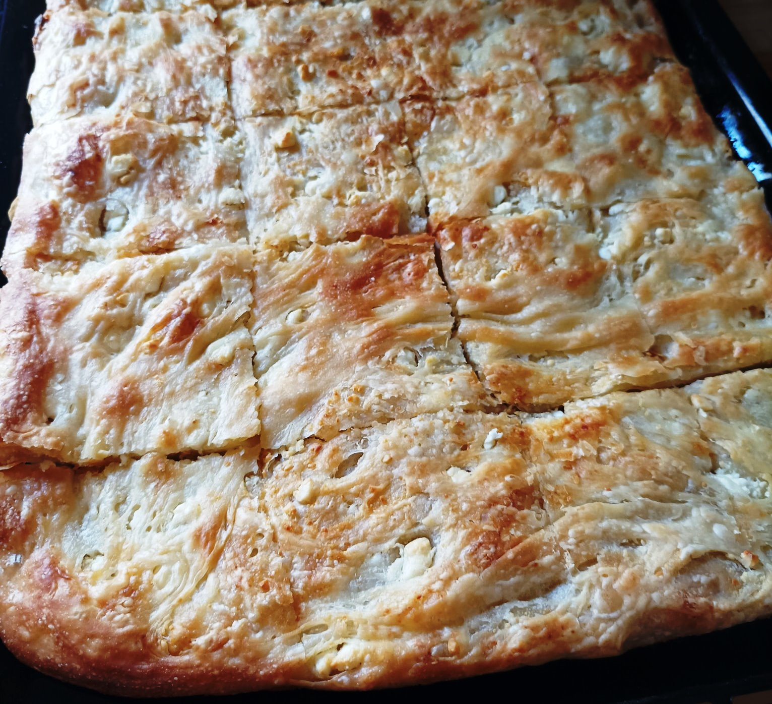 Έτοιμη, χρυσαφένια πίτα χωρίς πλαστεί σε ένα ταψί, φρεσκοψημένη.