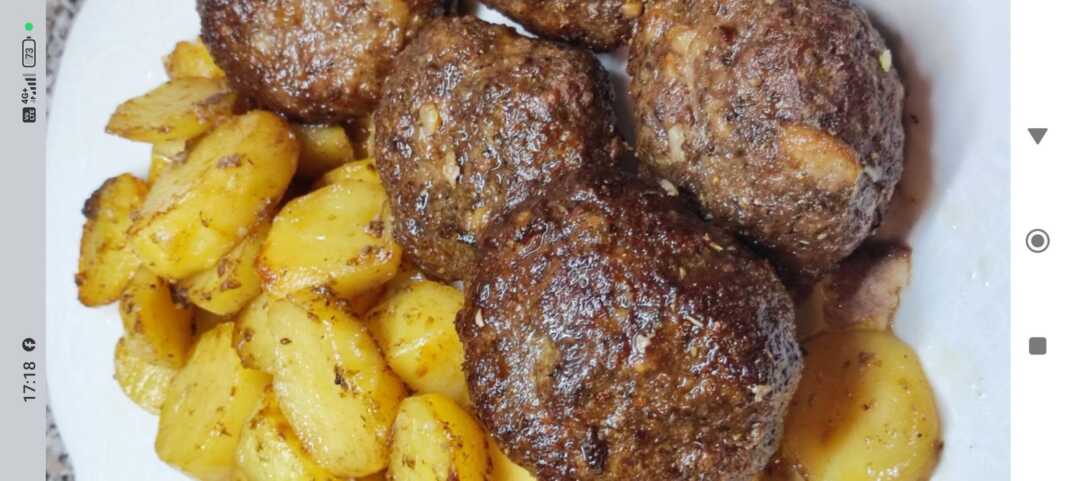 Ένα ταψί γεμάτο με αφράτα μπιφτέκια και πατάτες κοκκινιστές στο φούρνο, έτοιμα για σερβίρισμα