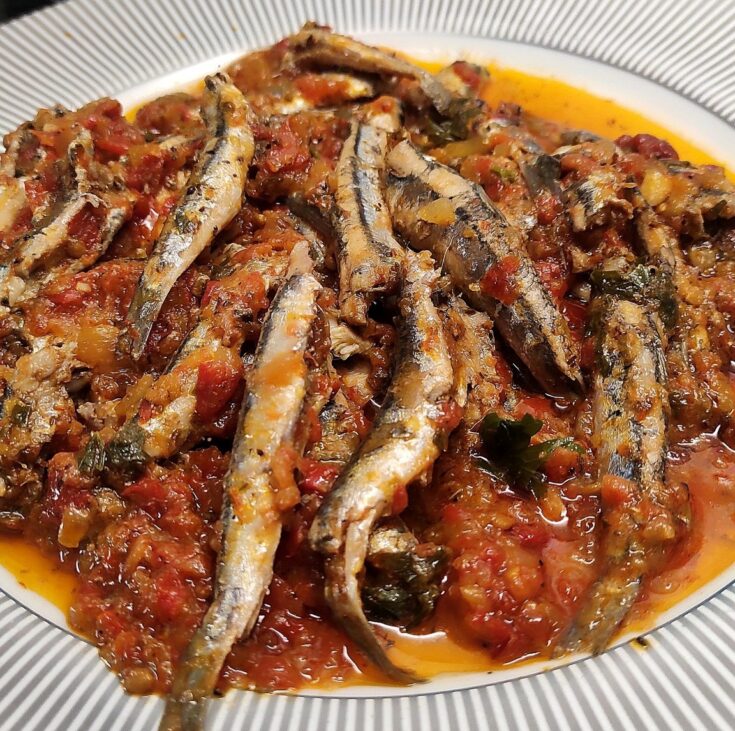 Μια πιατέλα με τηγανητό γαύρο με σάλτσα ντομάτας, πασπαλισμένο με φρέσκο μαϊντανό