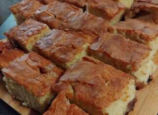 Ένα ολόκληρο κέικ σε κομματια με γιαούρτι, ψημένο μέχρι να ροδίσει, πάνω σε μια βάσ