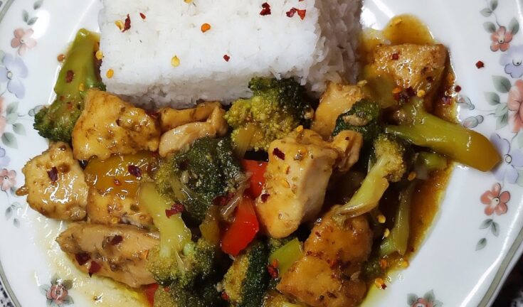 Ένα μπολ με κοτόπουλο stir-fry με λαχανικά και σάλτσα σόγιας, σερβιρισμένο πάνω σε ρύζι μπασμάτι