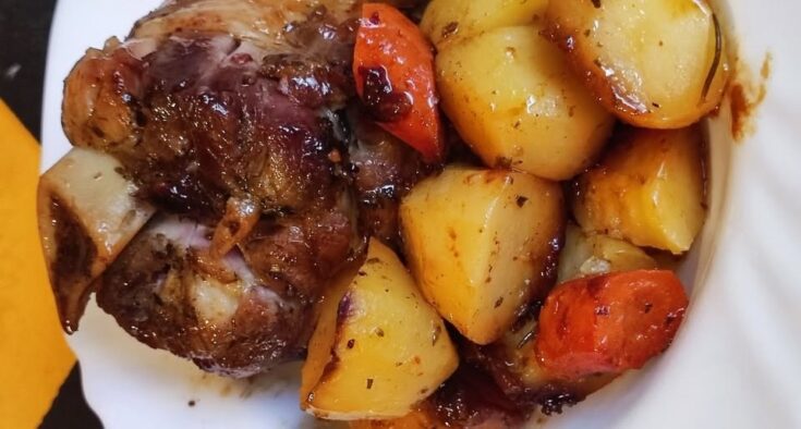 Ένα ζουμερό χοιρινό κότσι στη γάστρα με ροδοκοκκινισμένες πατάτες, έτοιμο για σερβίρισμα