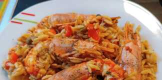 Μια κοντινή φωτογραφία από ένα πιάτο με ζεστό, λαχταριστό κριθαρωτό με γαρίδες και λαχανικά