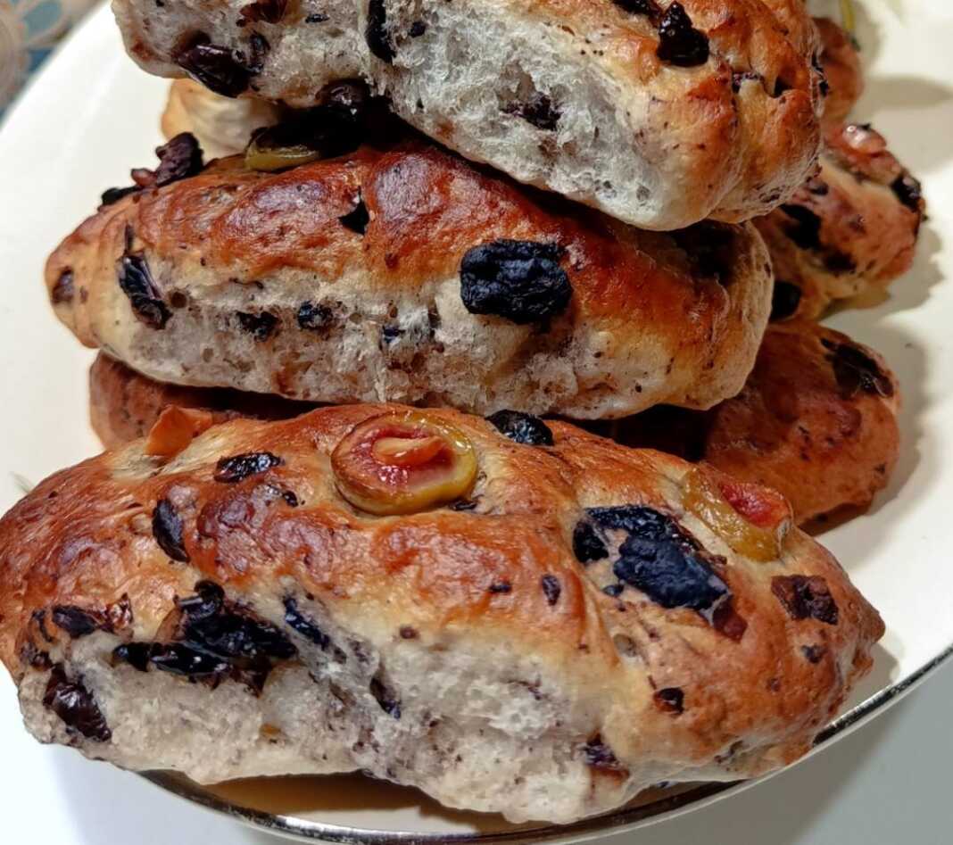 Ένα ταψί με φρεσκοψημένα Ελιόψωμα, λαμπερά από το βούτυρο και με ελιές να ξεπροβάλλουν από τη ζύμη