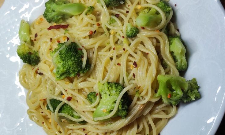 Ένα μπολ με ζεστό σπαγγέτι με μπρόκολο και σκόρδο, γαρνιρισμένο με φρέσκα μυρωδικά.