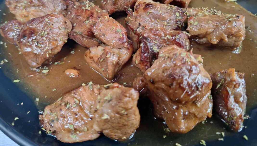 Μια χοιρινή τηγανιά με λεμόνι και κρασί στο τηγάνι, με πλούσια, δεμένη σάλτσα