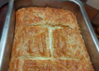 Μια χρυσαφένια τυρόπιτα με μπεσαμέλ, φέτα και κότατζ, κομμένη σε κομμάτια, έτοιμη για σερβίρισμα