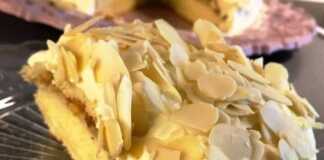 Ένα κομμάτι τούρτας αμυγδάλου σε πιάτο, που φαίνονται οι στρώσεις της κρέμας και του παντεσπανιού