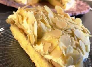 Ένα κομμάτι τούρτας αμυγδάλου σε πιάτο, που φαίνονται οι στρώσεις της κρέμας και του παντεσπανιού