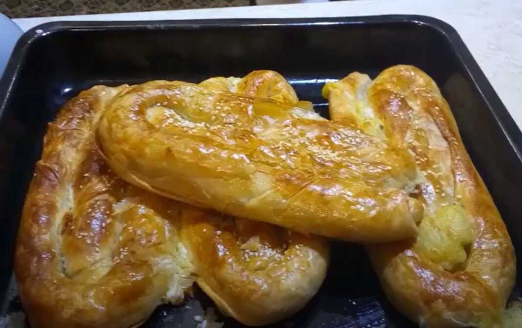 Η τελική πατατόπιτα με ζύμη τριών υλικών, ψημένη, χρυσαφένια και πασπαλισμένη με σουσάμι