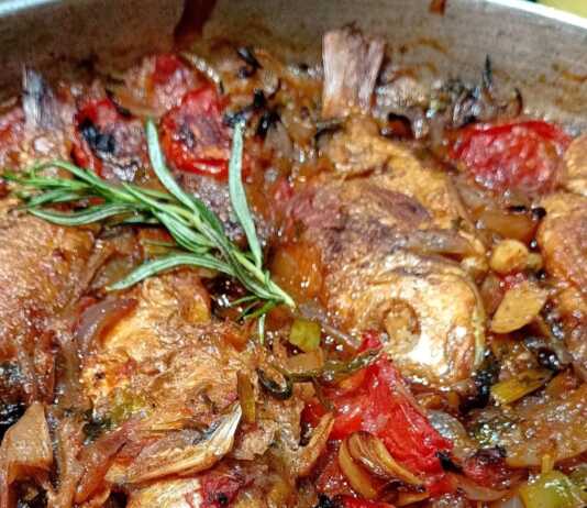 Λιθρινάκια πλακί ψημένα στο ταψί με πλούσια σάλτσα ντομάτας και κρεμμυδιών, έτοιμα για σερβίρισμα