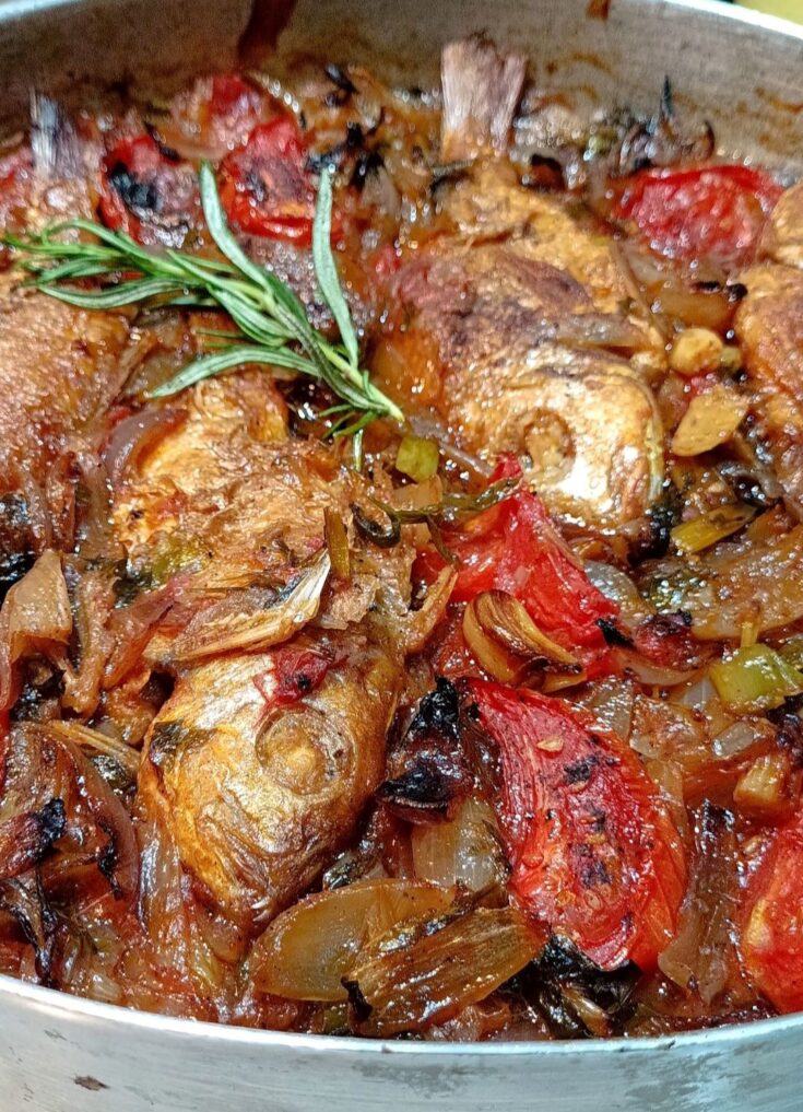 Λιθρινάκια πλακί ψημένα στο ταψί με πλούσια σάλτσα ντομάτας και κρεμμυδιών, έτοιμα για σερβίρισμα