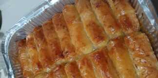 Ατομικά γαλακτομπουρεκάκια σε ρολό με χρυσαφένιο φύλλο κρούστας ποτισμένα με σιρόπι και πασπαλισμένα με κανέλα σε πιατέλα