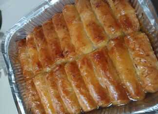 Ατομικά γαλακτομπουρεκάκια σε ρολό με χρυσαφένιο φύλλο κρούστας ποτισμένα με σιρόπι και πασπαλισμένα με κανέλα σε πιατέλα